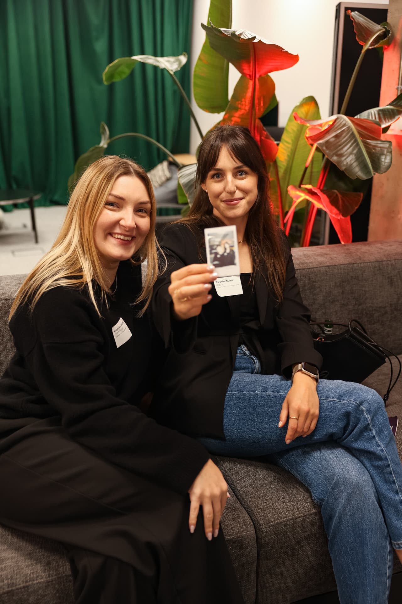 Two guests on a sofa holding up an instant photo